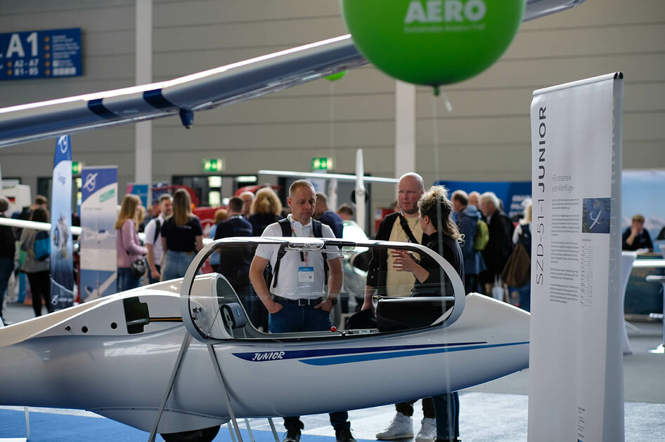 Besucher betrachten ein Segelflugzeug am AERO 2024 Messestand.